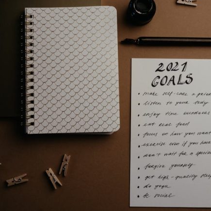 Aesthetic flatlay of notebooks and a 2021 goals list in elegant calligraphy.