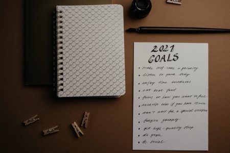 Aesthetic flatlay of notebooks and a 2021 goals list in elegant calligraphy.